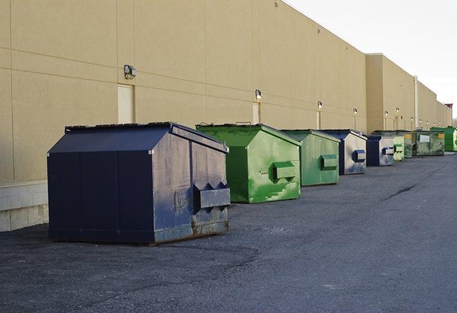 a row of yellow and blue dumpsters at a construction site in Jamestown